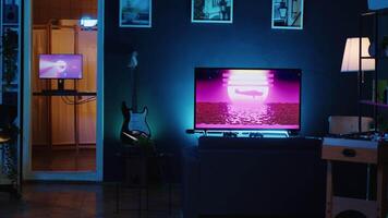 Empty personal studio illuminated with RGB lights used for internet video production. Dimly lit living room filled with interior home decor and 3D animations running in background