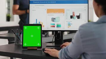especialista trabajos con pantalla verde tableta en abierto piso plan oficina, presentación aislado monitor en moderno dispositivo. mujer de negocios utilizando ordenador personal monitor y blanco chromakey diseño en mini pantalla. video