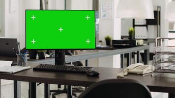 Greenscreen desktop in coworking space pc placed on workstation, open floor plan business office. Computer monitor showing isolated chromakey template with blank mockup display. video