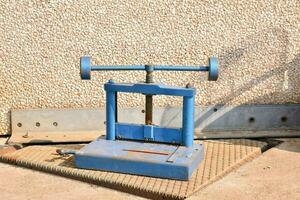 un azul máquina con ruedas en eso sentado en un cemento piso foto