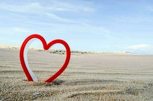 a heart shaped plastic toy on the sand photo