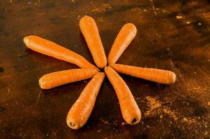 five carrots arranged in a star shape on a wooden table photo