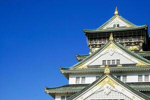 Osaka City, JP, 2019 - Closeup and crop Osaka castle on bright blue sky background. photo