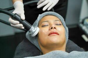 Closeup Asian beauty woman having therapy to stimulate facial skin and facial ultrasonic skincare treatment by professional cosmetologist wellbeing. photo