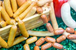 Closeup and crop variety German sausage with wooden box on decoration plastic green grass background. photo