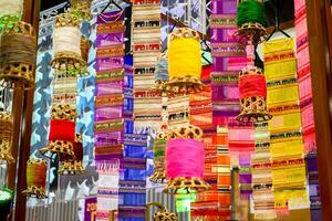 Closeup decorative wicker lantern and Lanna fabric long flags hang on hotel lobby ceiling and blurry background. photo