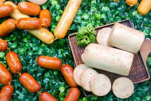 Closeup and crop variety German sausage with wooden tray on decoration plastic green grass background. photo