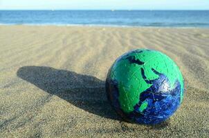 a green and blue globe on the beach photo