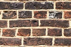 un ladrillo pared con un pocos pequeño agujeros en eso foto