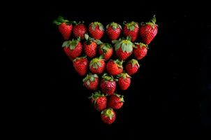 strawberries arranged in a triangle shape on a black background photo