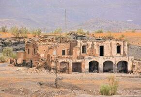 an old building in the desert with a mountain in the background photo