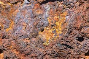 a close up of a rusty rock with a yellow paint photo