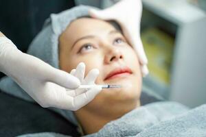 Closeup hands of beauty doctor in medical grove holding beauty skin syringe injecting the customer's face. Beauty skin concept photo