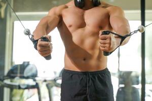 Closeup and crop perfect body of Asian guy playing weight lifting machine at fitness center. photo