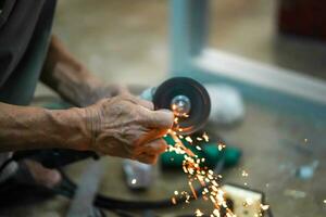 Closeup hands of the master saw the metal holding electric angle grinder working with sparks in metalworking at construction site. photo