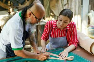 Team of leathers maker is drawing a design on leather sheet in leather workshop. photo