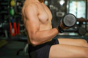 Closeup and crop perfect body of Asian guy playing weight training at fitness center. photo