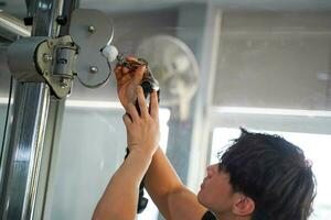 Closeup Asian young officer of the gym and fitness trainer checking fitness equipment at fitness center photo