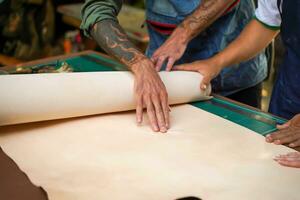 Closeup and crop hands of leather craftsman touching at the flaw of the white leather. photo