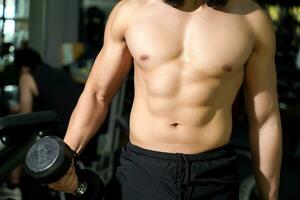 Closeup and crop perfect body with weight training at fitness center. photo