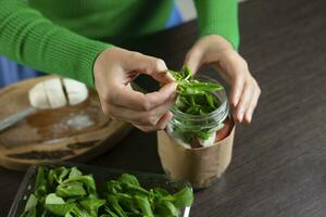 Woman making vegan salad in jar with chickpea. Cooking healthy food. photo