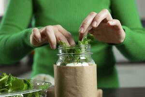 Woman making vegan salad in jar with chickpea. Cooking healthy food. photo