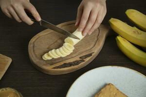 Woman slices banana for breakfast. photo