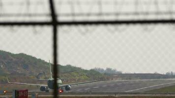 Rear view of a commercial airplane accelerating and taking off. View of the runway through the airport fence video