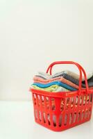 Multi-colored towels lie in a red laundry basket on a white background. Laundry and ironing. photo