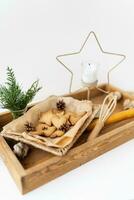 Preparation of gingerbread cookies, different gingerbread cookies of different shapes lie on a wooden tray along with a star candle, a whisk and a bouquet of arborvitae. Holiday concept. photo