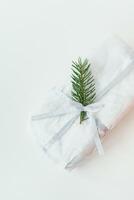 A homemade Christmas stollen sealed in white craft paper, along with a sprig of a Christmas tree, lies on a white background. Gift wrap. photo