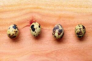 Quail eggs on a wooden background. Quail eggs in a row photo