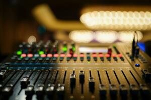 Closeup of sound mixer board with faders up, buttons and background in bokeh photo