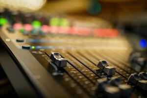 Closeup of an audio console, mixer with faders up and background in bokeh photo