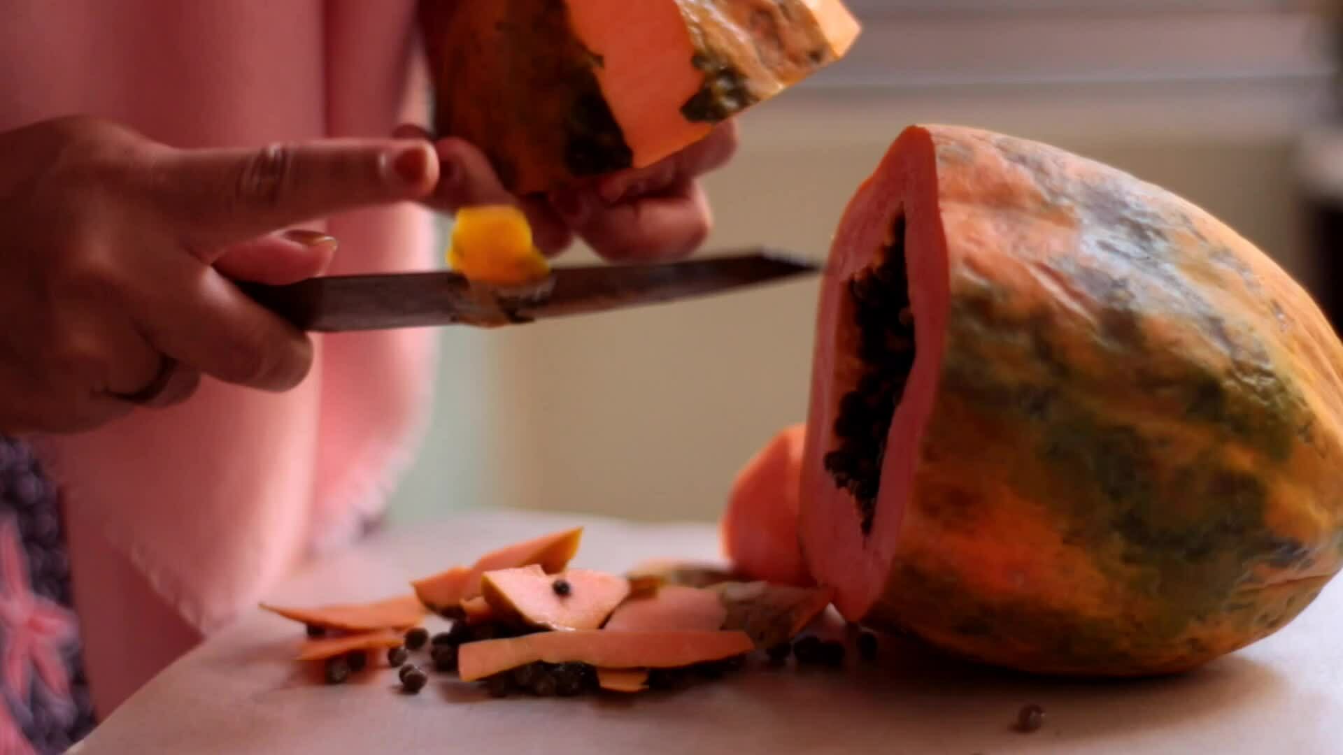 slicing and peeling fresh papaya fruit. Papaya in Latin is Carica