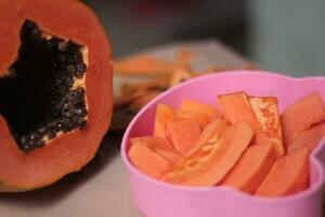 cortar papaya Fruta es servido en un rosado envase y Listo a comer para salud. foto