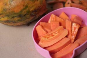 cortar papaya Fruta es servido en un rosado envase y Listo a comer para salud. foto