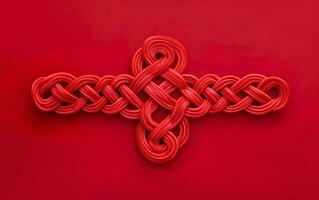 Chinese symmetrical ornament, a red knot isolated on red background. AI Generative photo