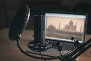 Home studio for podcasts. Large black Microphone on stand, notebook and notebooks on desk. Interior. Closeup photo