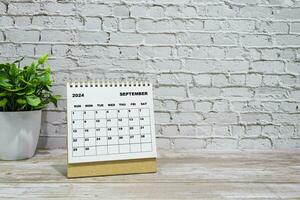 blanco septiembre 2024 calendario en oficina de madera escritorio con en conserva planta. foto