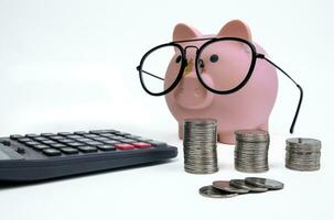 Glasses piggy bank with tower of coins and calculator photo