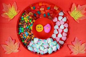 Set of different tasty candies in a red candy box on red background. variety of sweets and candies photo