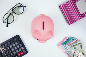 Financial concept with piggy bank, notebook, glasses, calculator and stack of indonesian currency money photo