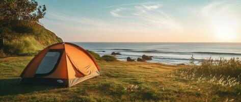 Camping tent and camping equipment on green grass with sea view background AI generated photo