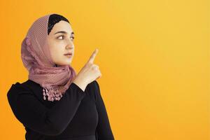 Portrait of stylish Iranian woman. Elegant Muslim woman in hijab pointing with hands to empty space. Copy space for your text. Beautiful Muslim female isolated photo