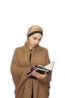 Stylish Muslim woman in warming knitted cardigan with Islamic headscarf. Portrait of cute middle-eastern model in warming and comfort clothes. Stock photo of Islamic clothing, fashion.