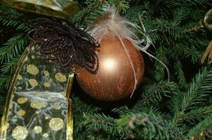 Golden ball with decorative ribbon on the background of a Christmas tree. Festive New Year background. photo
