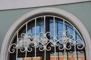 A window with an arch and an openwork white lattice on the wall of a building. Facade element. photo