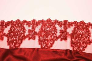 Red lace with an openwork pattern on a white background. Finishing element of lingerie, negligee. photo