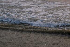 foam of sea or ocean waves against the backdrop of the setting sun photo